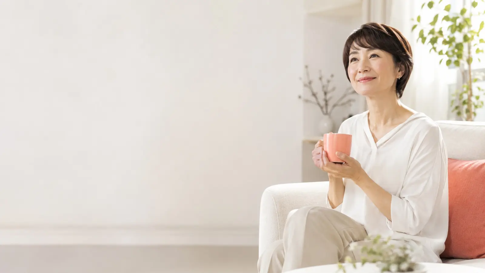 あたたかい飲み物とひざ掛けでくつろぐ女性