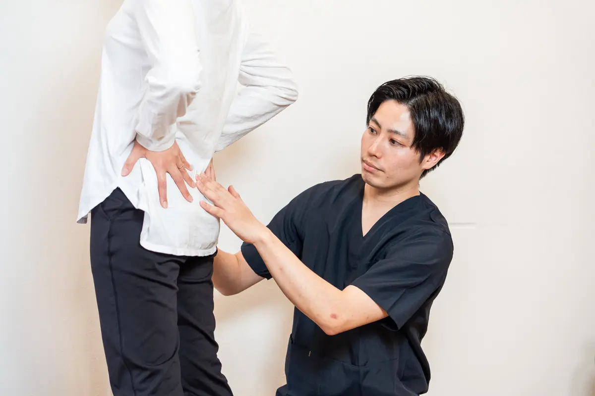 施術者が立った姿勢で腰の状態を確認している様子