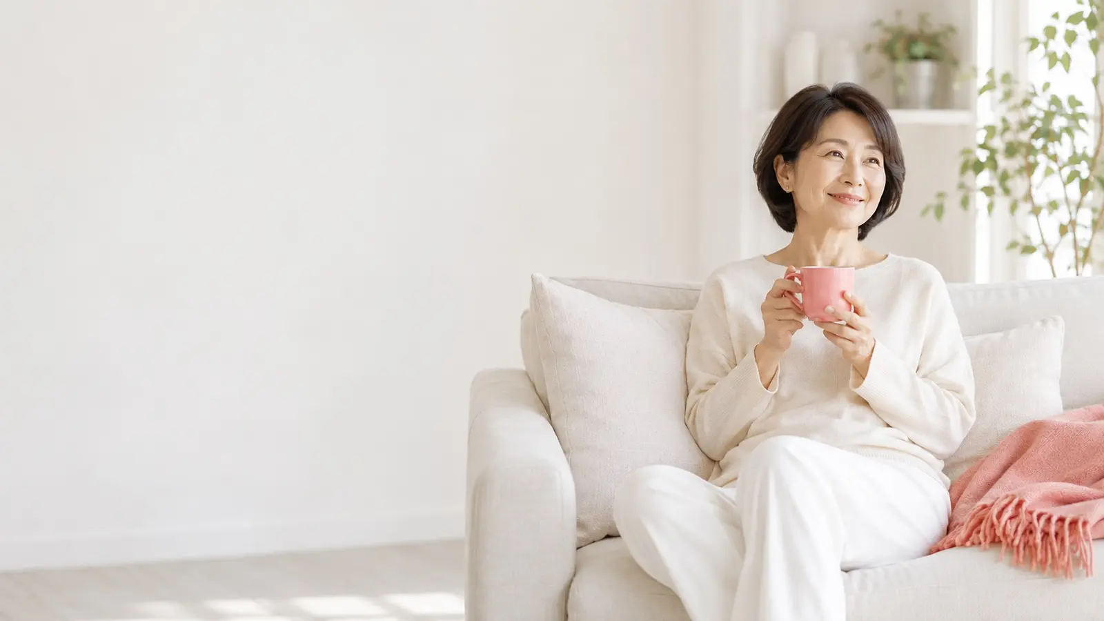 ソファでくつろいでお茶を飲む女性