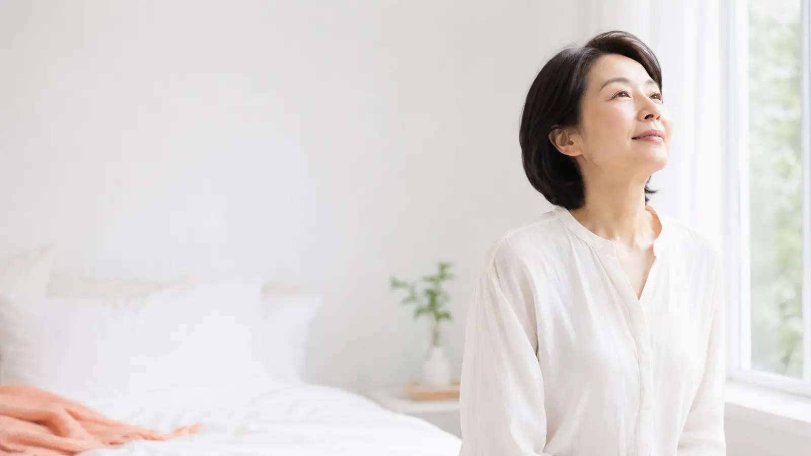 窓辺で深呼吸する・すっきり目覚めた女性