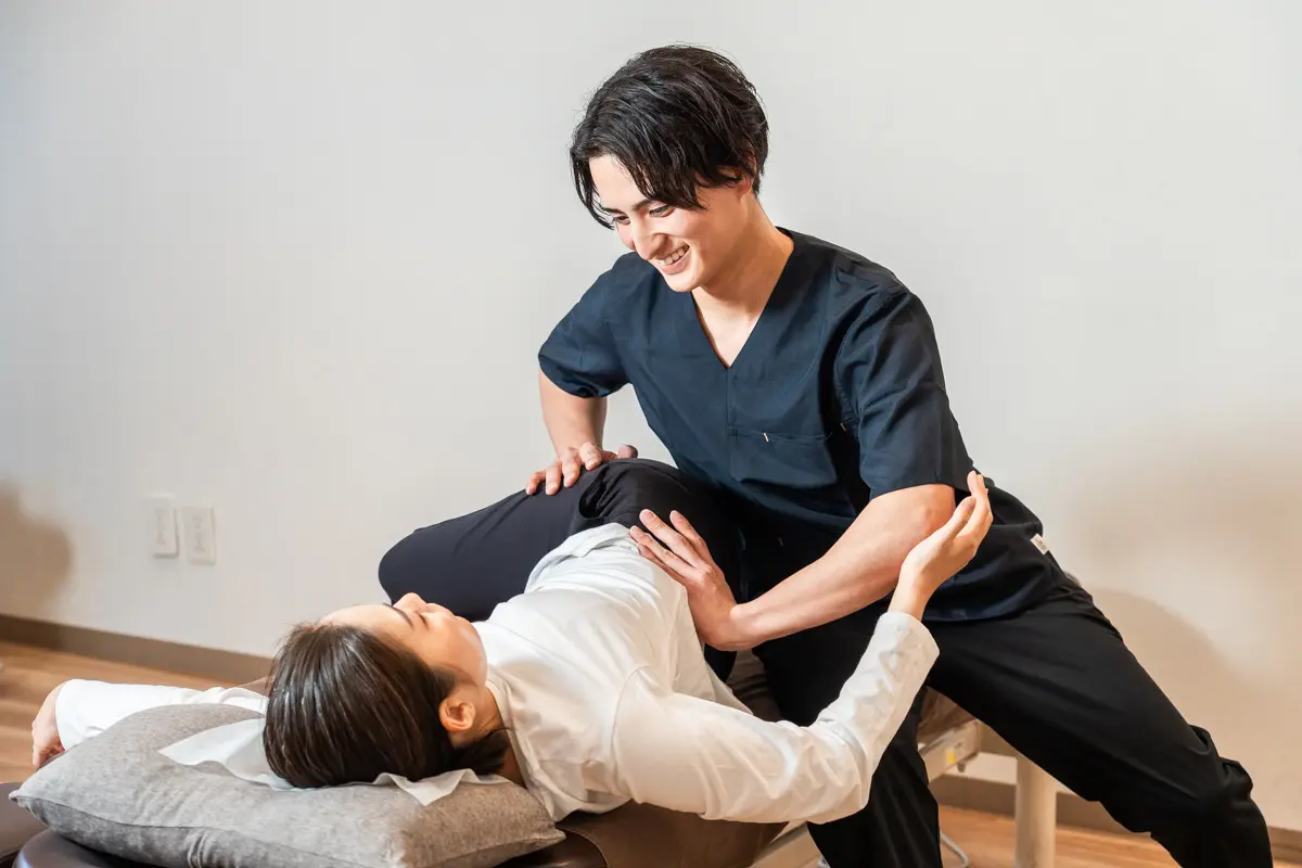施術者が体をひねる動きで筋肉・筋膜を整えている様子