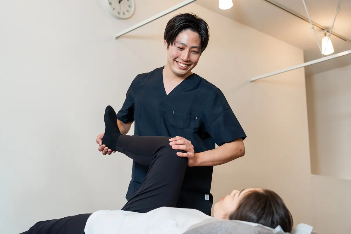 施術者が脚を動かして股関節の動きを確認している様子