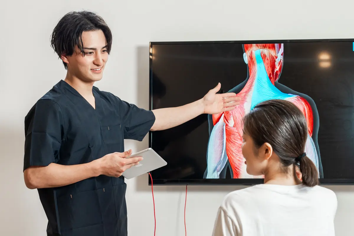 施術者が筋肉図を示しながら体の状態を説明している様子