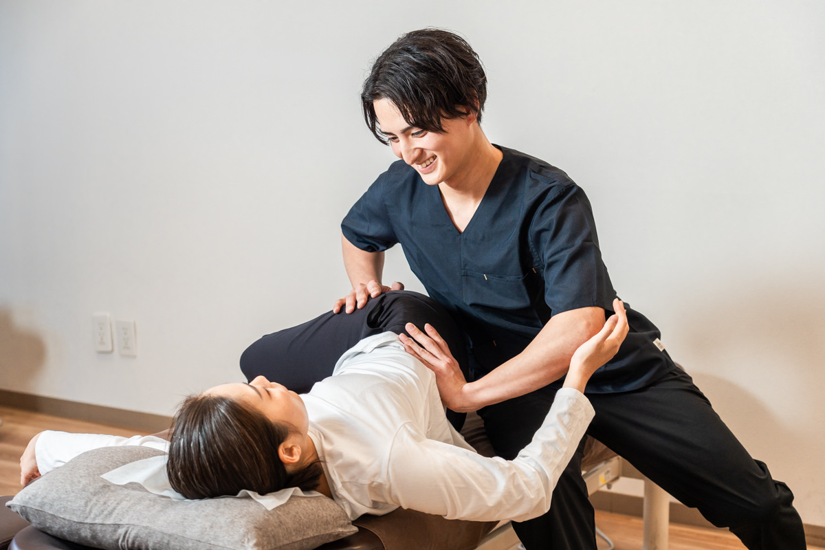 施術者が体をひねる動きで筋肉・筋膜を整えている様子