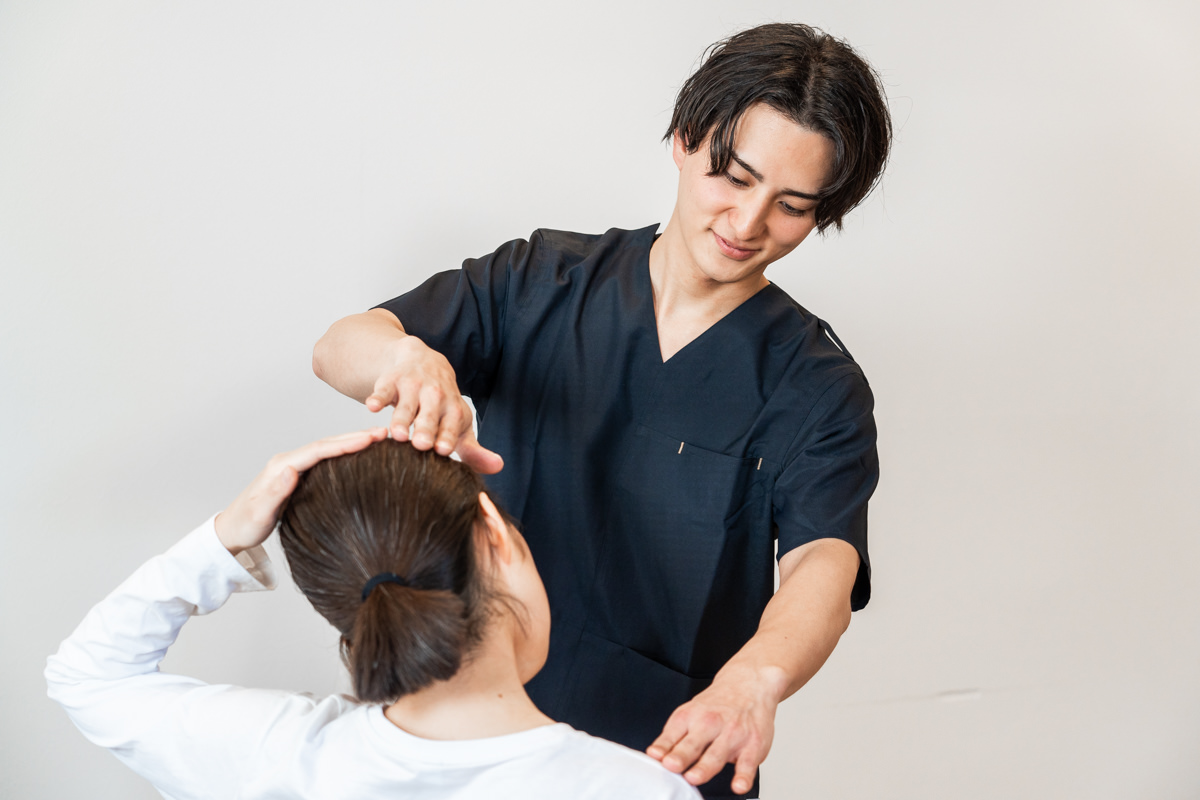 施術者が体に手を添えて状態を確認しながら進める様子